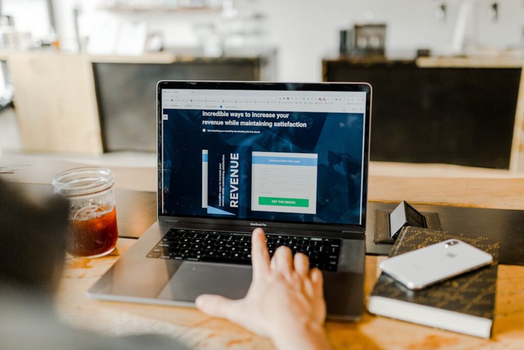 Dirigeant de PME B2B au travail sur son ordinateur avec carnet de notes et smartphone, outils de prospection commerciale