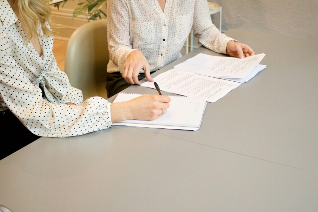 Deux personnes comparent des documents et prennent des notes lors d'un rendez-vous professionnel