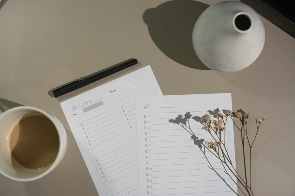 Liste numérotée à cocher posée sur une table claire, à côté d'un stylo et d'une tasse de café.