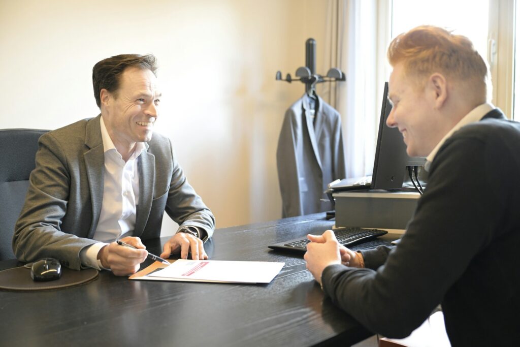 Un dirigeant de PME et un consultant commercial échangent autour d'une proposition posée sur le bureau