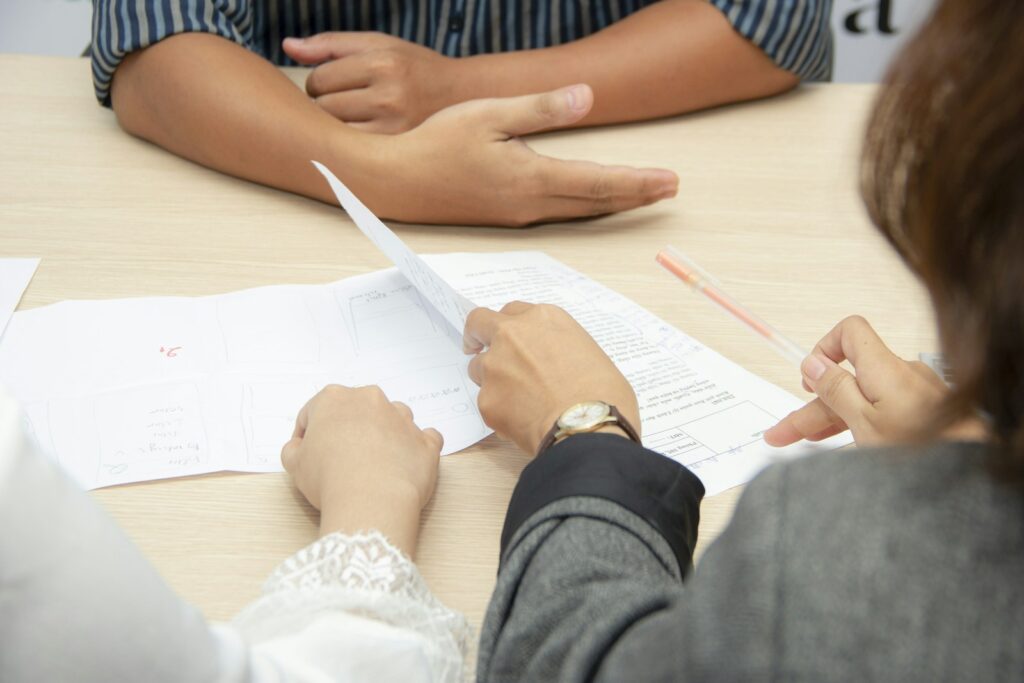 Deux dirigeantes comparent une proposition commerciale sur un bureau partagé, stylo et papier à la main