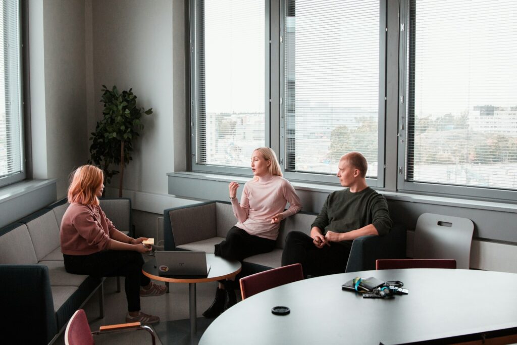 Trois professionnels en cadrage commercial dans un bureau lumineux, scène de décision dirigeant sur le choix entre commercial interne et prestataire externalisé