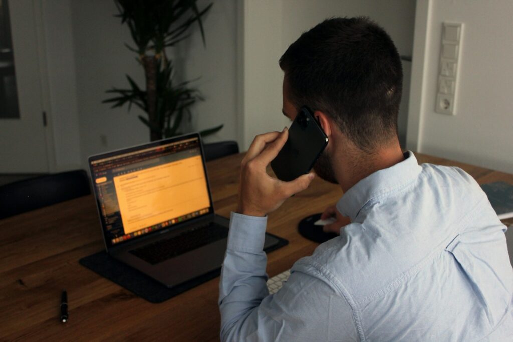 Dirigeant de PME en cours d'appel commercial face à son ordinateur portable, en train de traiter les objections d'un prospect B2B
