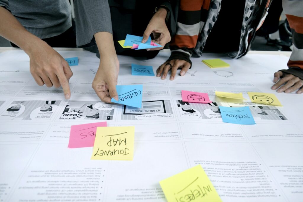 Équipe en atelier de positionnement commercial, post-its colorés et journey map sur grand schéma stratégique