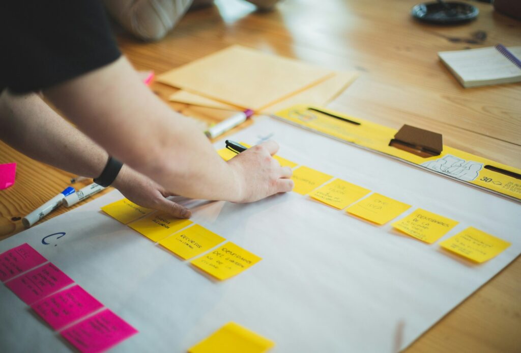 Mains qui organisent un plan d'action commercial en post-it sur une table de travail