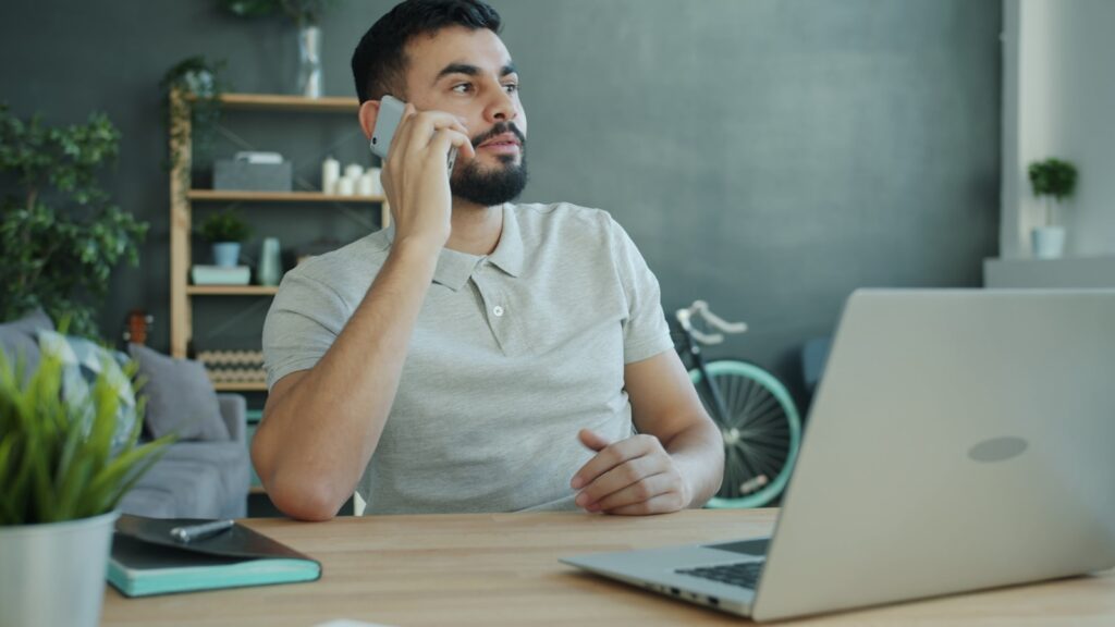 Dirigeant de PME au téléphone à son bureau, l'air pensif, hésitant à relancer un compte B2B resté silencieux
