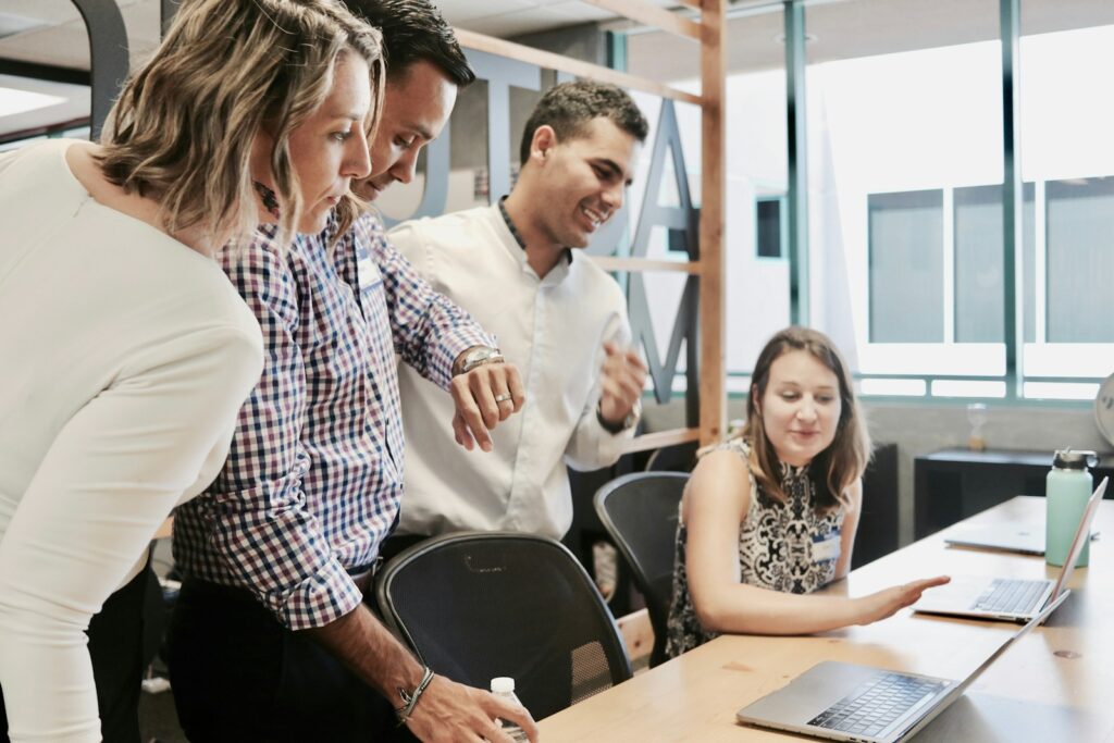 Équipe dirigeante de PME B2B en délibération autour d'un écran sur la décision d'externaliser ou d'internaliser sa prospection commerciale