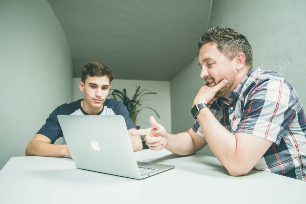 Mentor commercial qui explique une approche de prospection à un collègue devant un ordinateur portable
