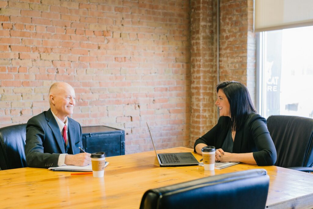 Séance d'accompagnement commercial entre un dirigeant de PME et une conseillère autour d'un ordinateur portable