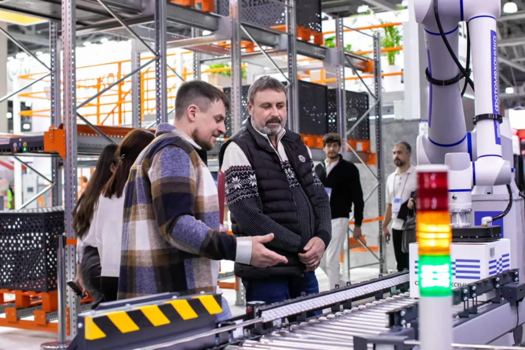 Deux professionnels en discussion devant une ligne de production automatisée dans une PME industrielle