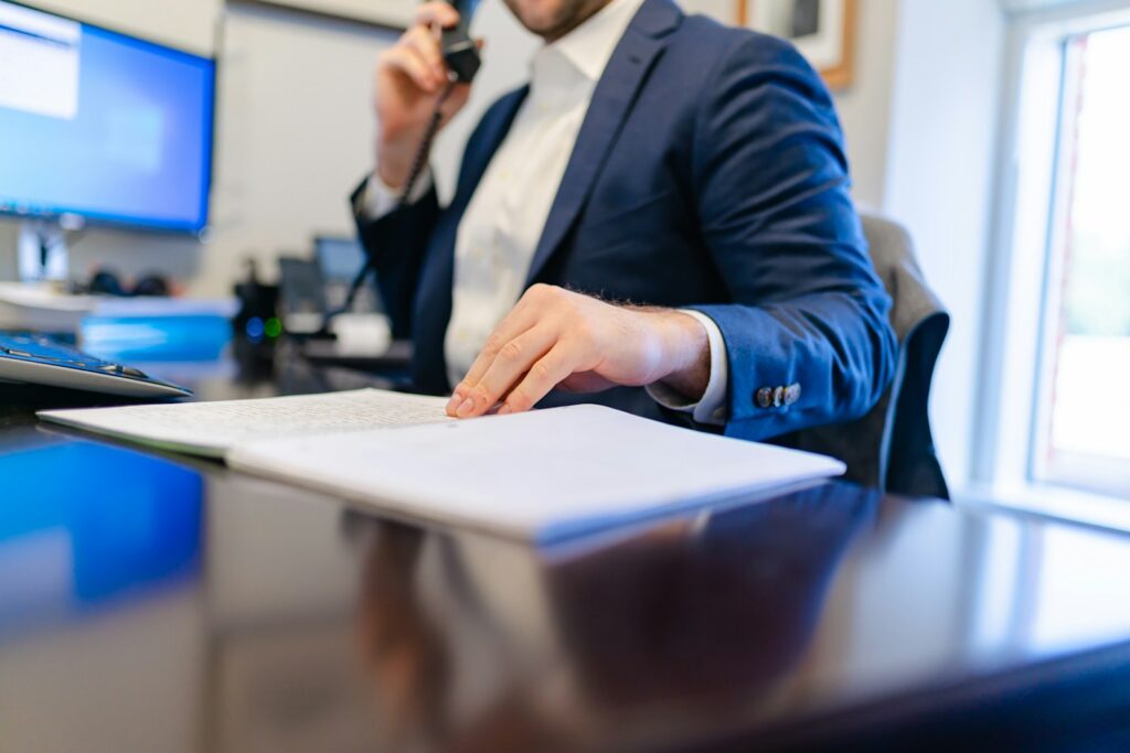 Dirigeant d'une PME de services en appel de prospection, prenant des notes sur un carnet à son bureau