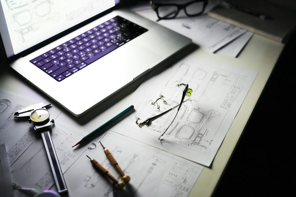 Plans techniques, ordinateur portable et outils de mesure posés sur le plan de travail d'un bureau d'études