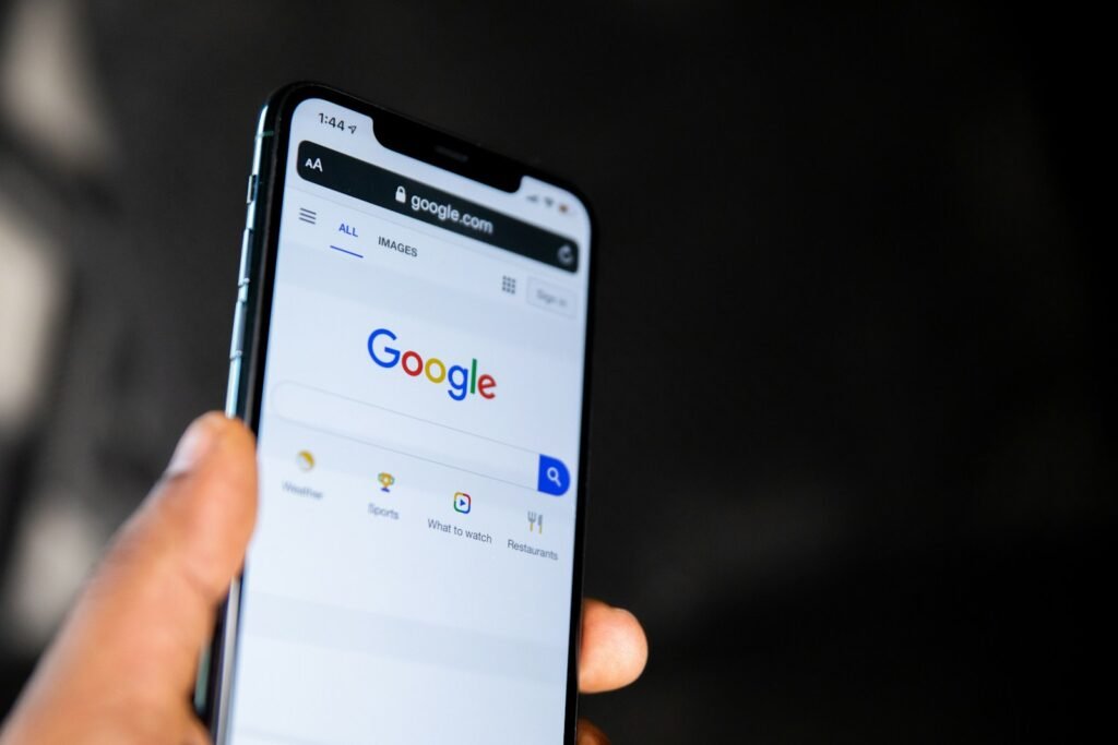 Main qui tient un téléphone ouvert sur la page de recherche Google, avant une recherche d'entreprise
