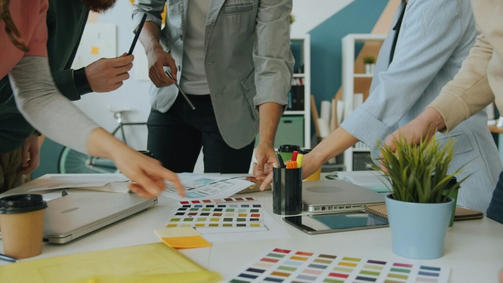 Équipe debout autour d'une table qui compare des nuanciers de couleurs pendant un atelier d'identité de marque