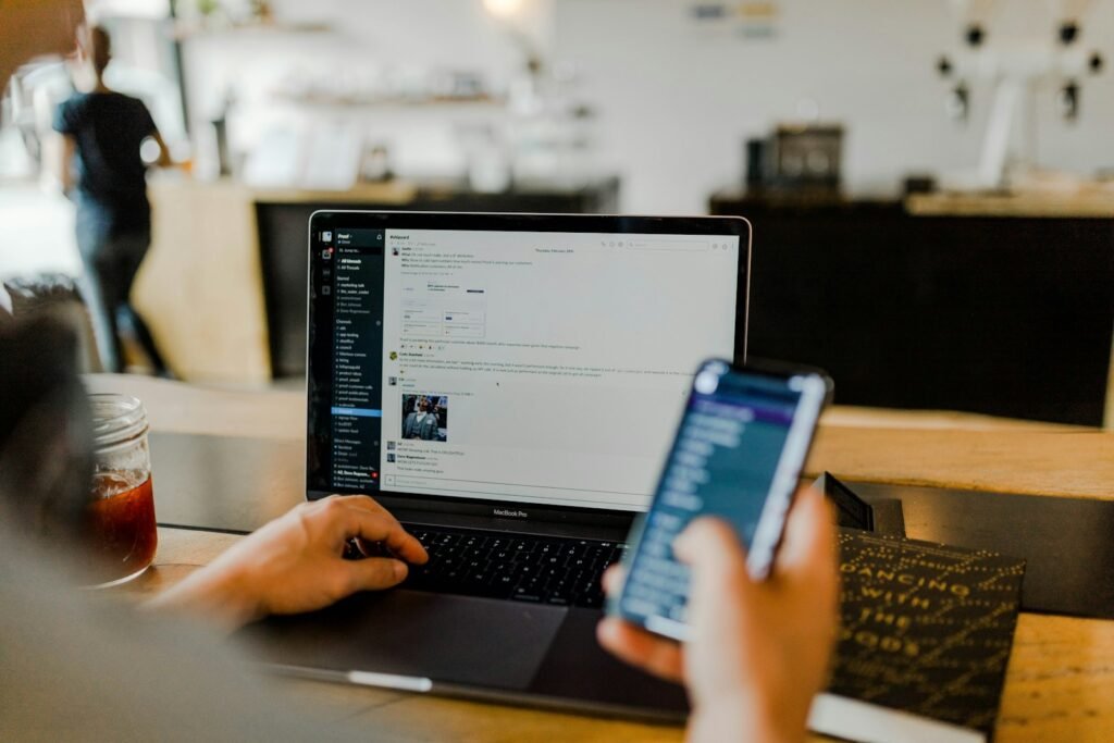 Dirigeant qui prépare une relance sur son téléphone, ordinateur portable ouvert sur la table