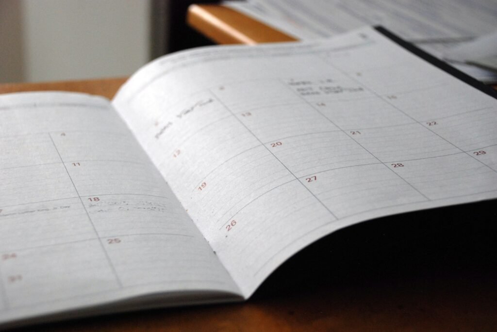 Agenda mensuel papier ouvert sur un bureau en bois, avec quelques rendez-vous notés à la main